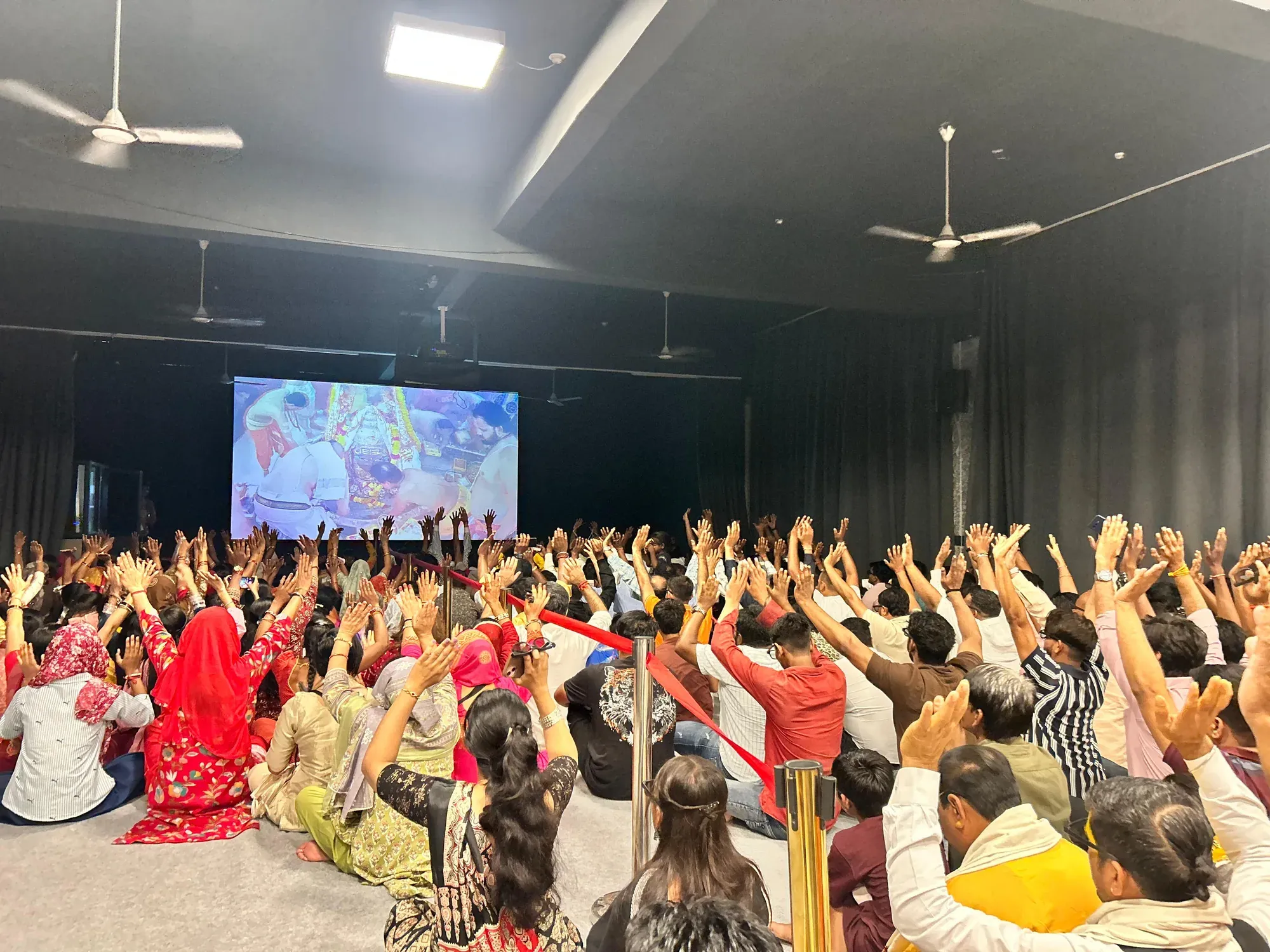 Devotees with raised hands in front of the screen